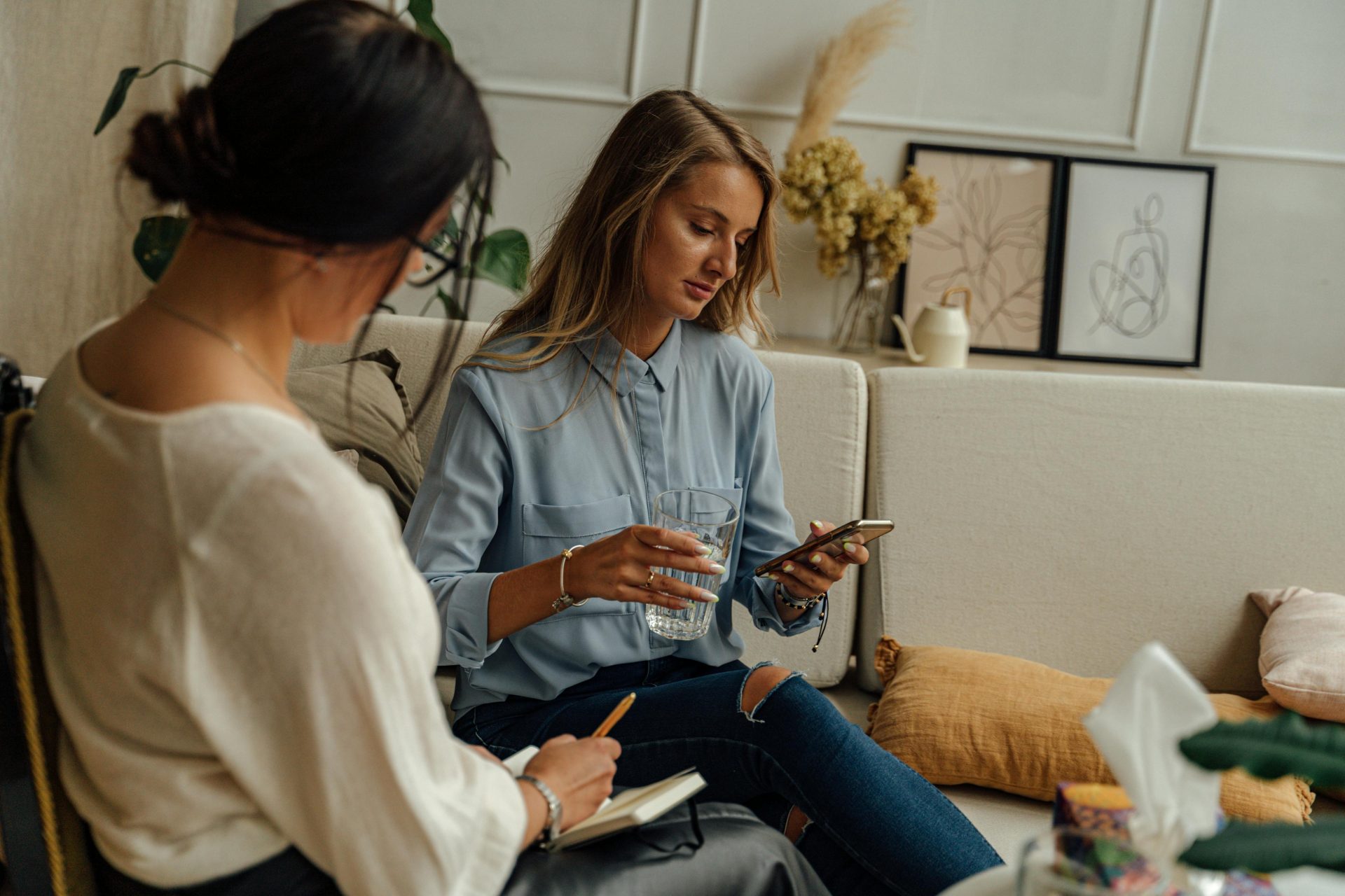 Two women engaged in a therapy session in a warm, stylish living room setting.